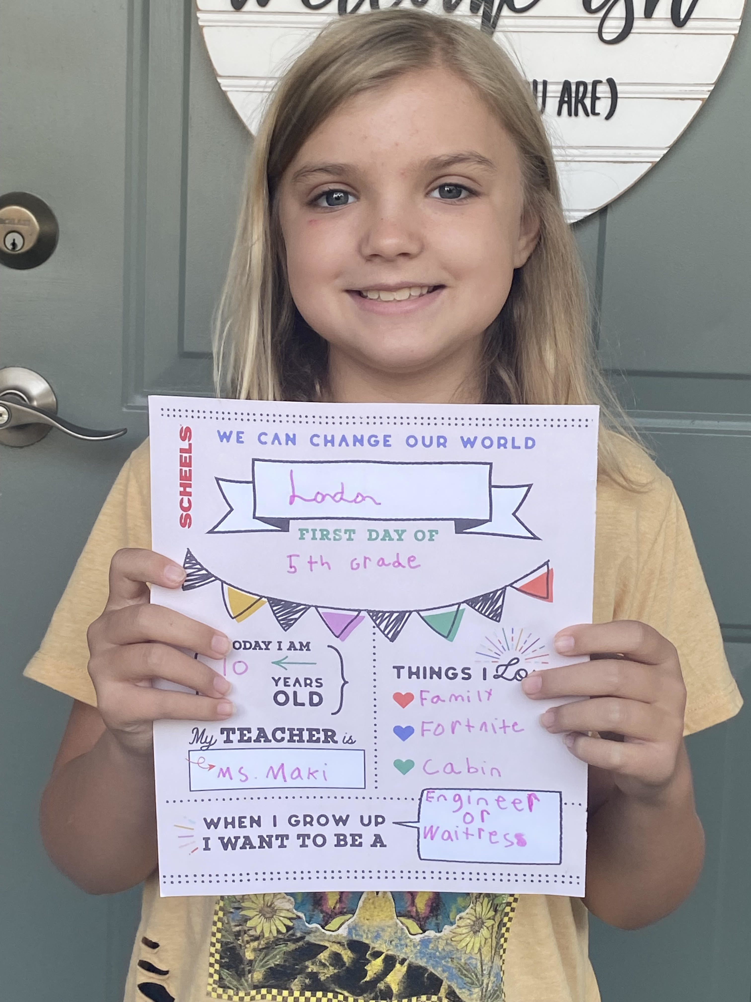Girl holding first day of school banner